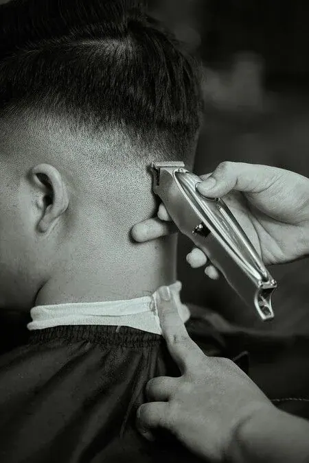 Barber shaping a neckline with clippers at Odry's Tamarindo